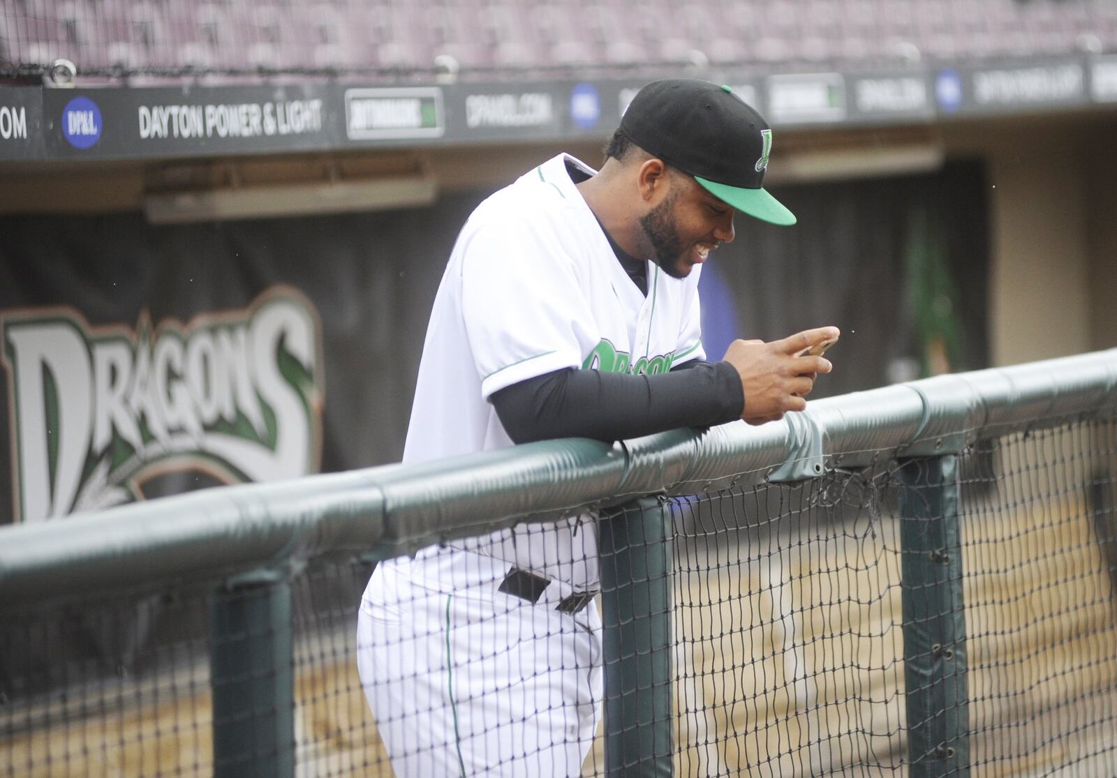Dragons catcher Hendrik Clementina checks a text message in the Dragons’ dugout prior to a final preseason workout at Dayton’s Fifth Third Field on Wednesday, April 4, 2018. MARC PENDLETON / STAFF