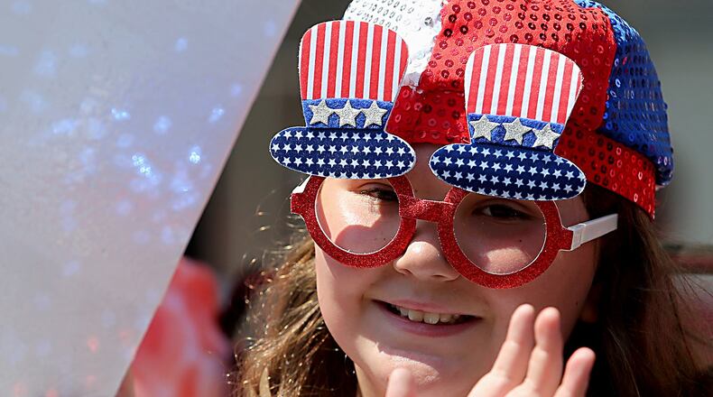 A young girl waves to spectators as she participates in the 4th of July parade in Hamilton Tuesday, July 4, 2017.