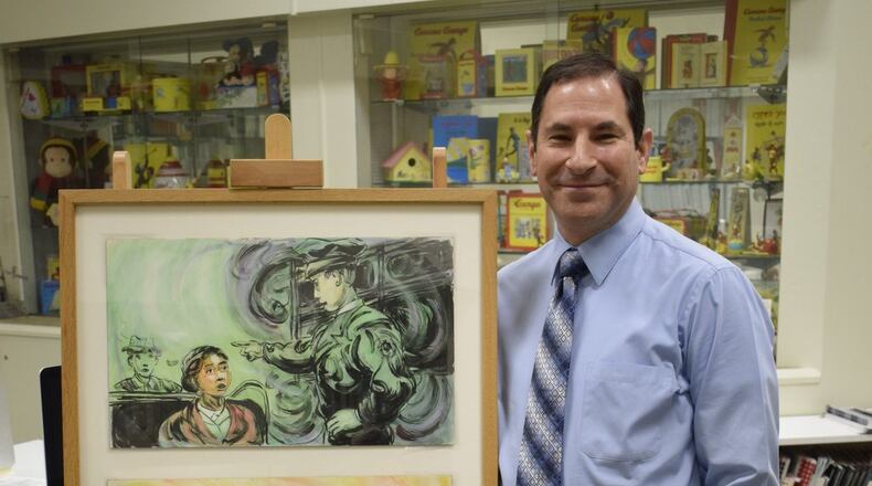 Jason Shaiman, curator of exhibitions, Miami University Art Museum stands in his office in front of his own classic Curious George collection. CONTRIBUTED