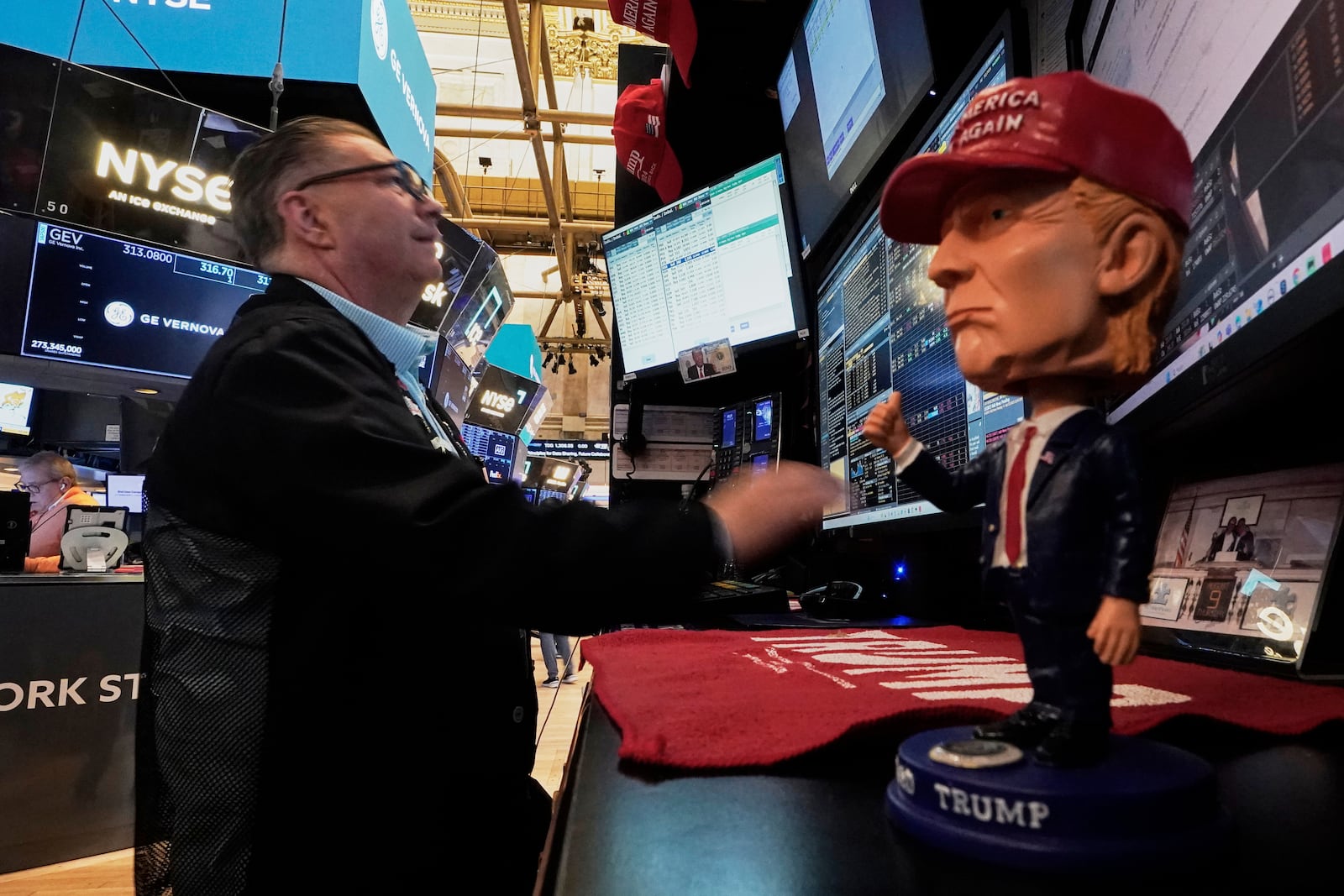 A Donald Trump bobblehead sits on the counter as trader Jonathan Mueller works on the floor of the New York Stock Exchange, Tuesday, April 22, 2025. (AP Photo/Richard Drew)