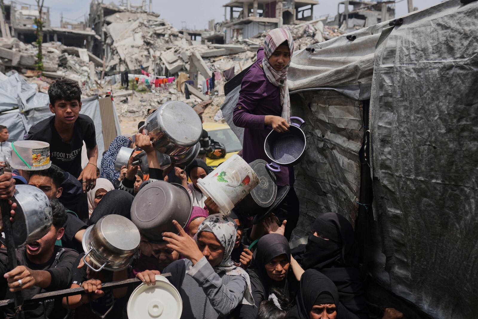 Palestinians struggle to get donated food at a community kitchen in Jabalia, northern Gaza Strip, Thursday, May 15, 2025. (AP Photo/Jehad Alshrafi)