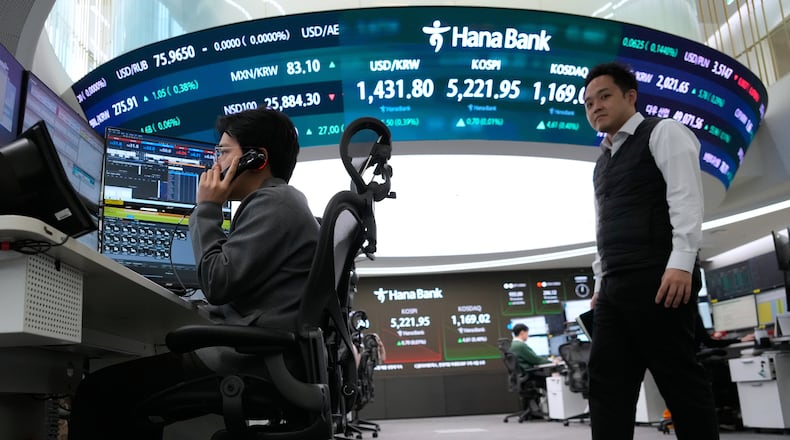 A currency trader talks on the phone near a screen showing the Korea Composite Stock Price Index (KOSPI), top center, and the foreign exchange rate between U.S. dollar and South Korean won, top center left, at the foreign exchange dealing room of the Hana Bank headquarters in Seoul, South Korea, Friday, Jan. 30, 2026. (AP Photo/Ahn Young-joon)