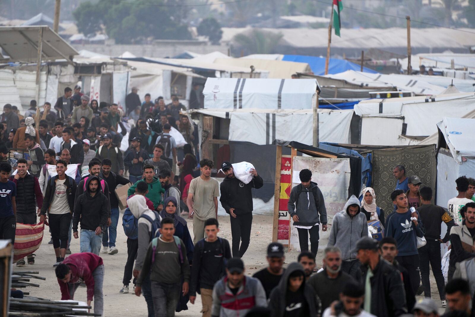 Palestinians carry bags filled with food and humanitarian aid provided by the Gaza Humanitarian Foundation, a U.S.-backed organization approved by Israel, in Khan Younis, southern Gaza Strip, on Tuesday, June 3, 2025. (AP Photo/Abdel Kareem Hana)