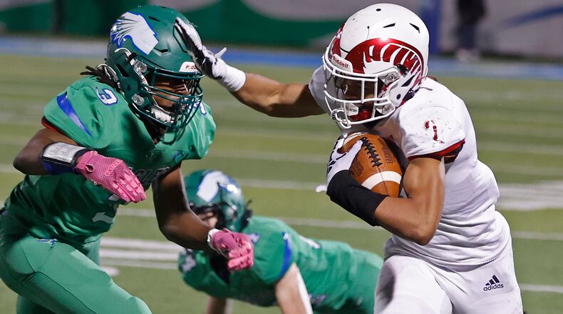 Trotwood-Madison's Quinten Johnson tries to avoid a tackle by CJ's Donaven Cummings as he carries the ball. BILL LACKEY/STAFF