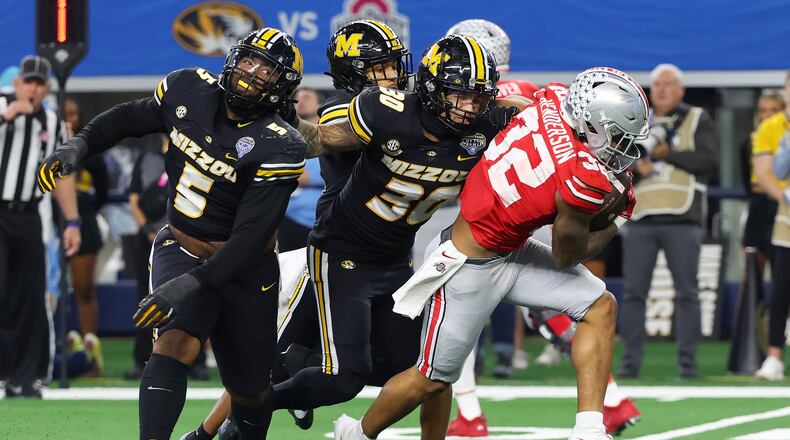 Ohio State running back TreVeyon Henderson (32) tries to get away from Missouri defensive lineman Kristian Williams (5) and linebacker Chuck Hicks (30) during the second half of the Cotton Bowl NCAA college football game Friday, Dec. 29, 2023, in Arlington, Texas. (AP Photo/Richard W. Rodriguez)