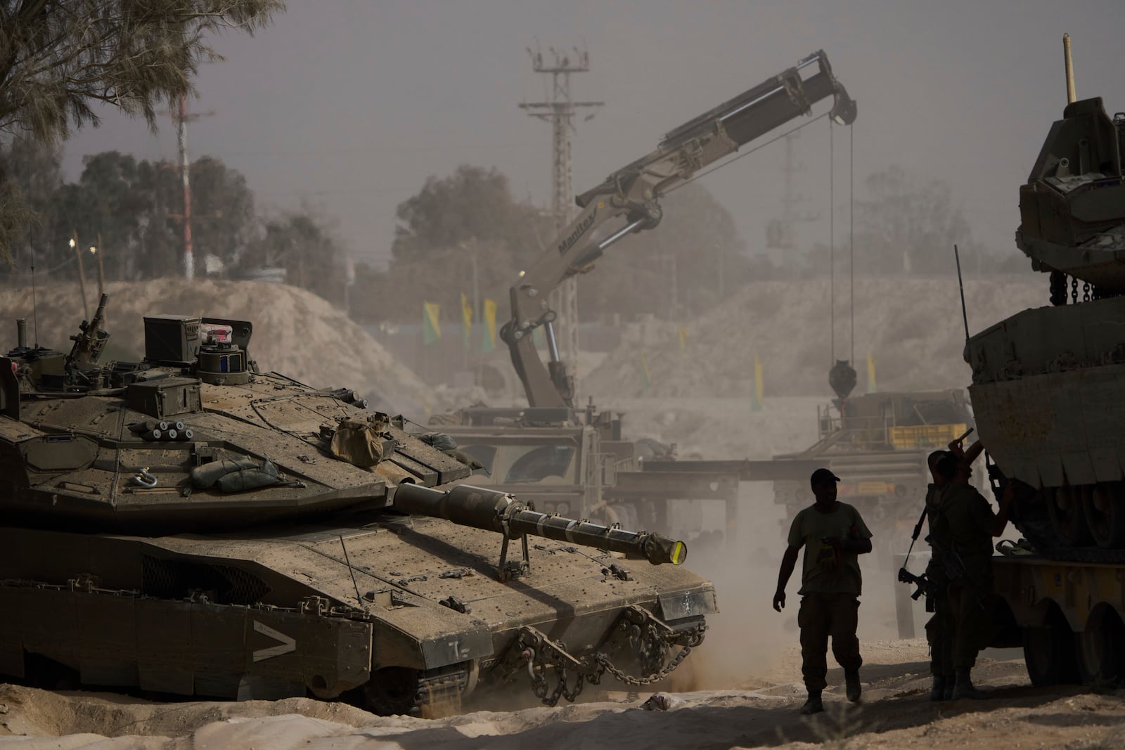 Israeli soldiers work on tanks at a staging area near the border with the Gaza Strip, in southern Israel, Tuesday, July 1, 2025. (AP Photo/Ariel Schalit)