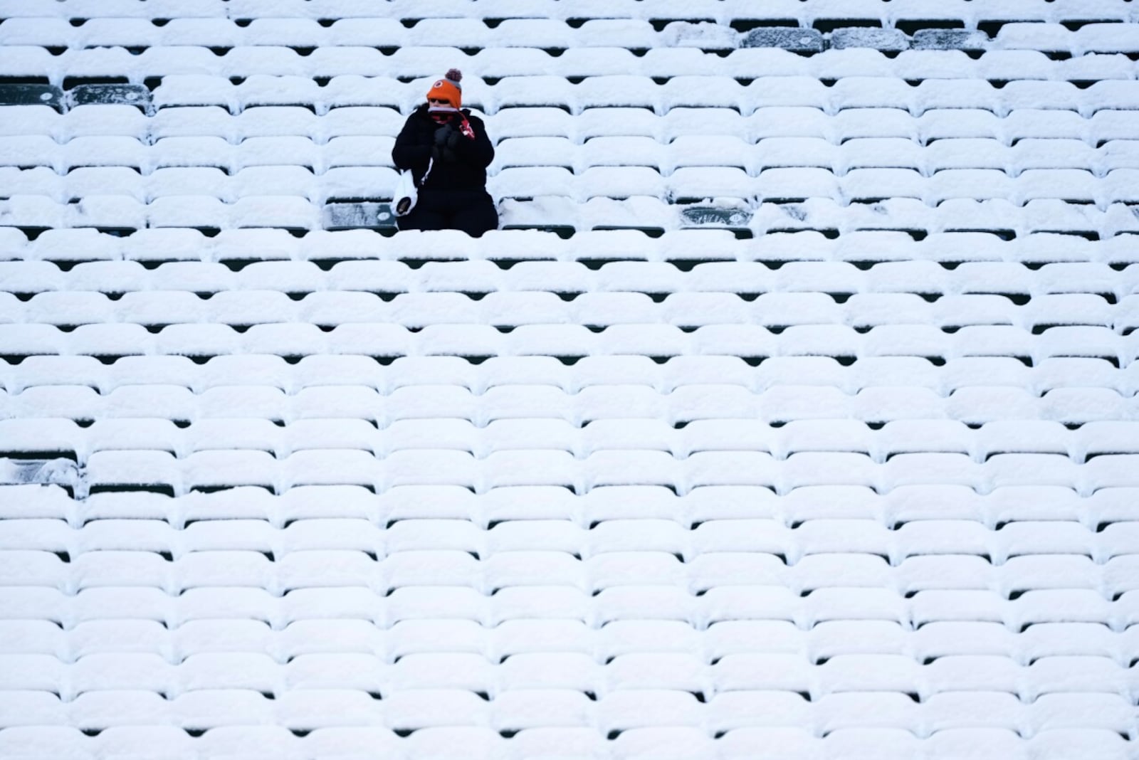 A fan sits in the stadium seats covered in snow before an NFL football game  between the Cincinnati Bengals and the Baltimore Ravens, Dec. 14 in Cincinnati. AP PHOTO/CAROLYN KASTER