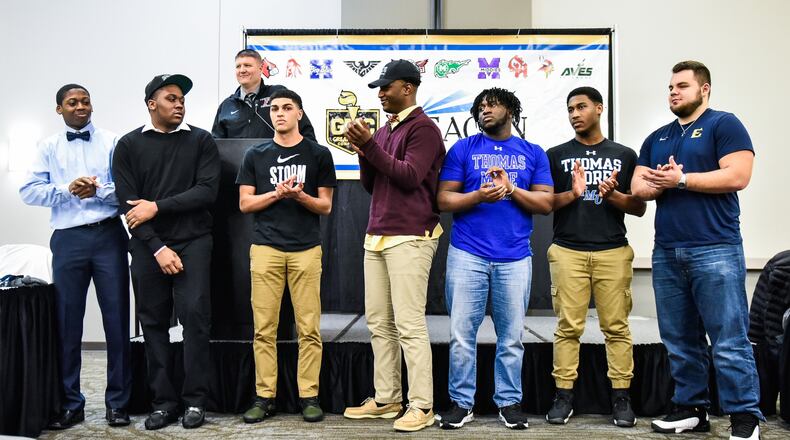 Fairfield head football coach Jason Krause (at podium) speaks about eight FHS players who have signed to play college football during the Greater Miami Conference National Signing Day event Wednesday at the Sharonville Convention Center. Left to right are Allen Caldwell (Pikeville), Mekiyell Muhammad (Lake Erie), Peyton Brown (Lake Erie), Jeff Tyus (Charleston), Greg Fitzpatrick (Thomas More), Del Thomas (Thomas More) and Jacob Hensley (East Tennessee State). Erick All (not pictured) signed early with Michigan and is already taking classes. NICK GRAHAM/STAFF