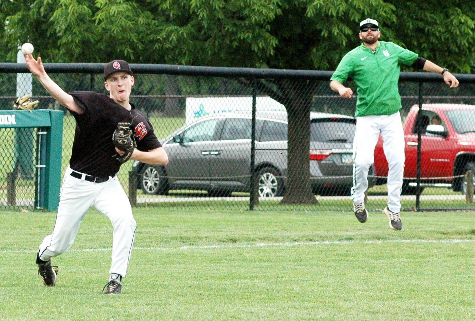 Oak Hills pitcher Wyatt Fisher throws to first base as Badin coach Brion Treadway jumps to get a better view during Thursday’s Division I sectional baseball game at Alumni Field in Joyce Park. Host Badin won 11-0 in five innings. RICK CASSANO/STAFF