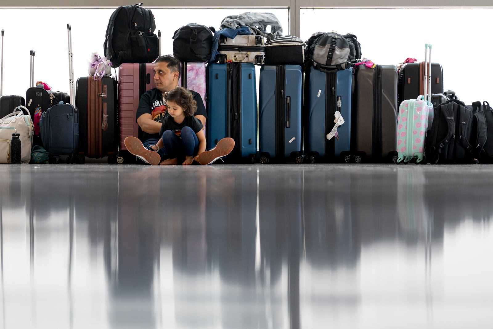 FILE - Samuel Tadros and his daughter Serenity 3, sit with the family's bags after their flight to New York was cancelled at the Nashville international Airport Thursday, May 23, 2024, in Nashville, Tenn., ahead of Memorial Day. (AP Photo/George Walker IV, File)