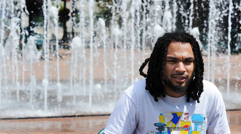 Jeremiah Peters, 23, talks about the importance of governments communicating about water quality with their citizens while sitting in front of the interactive fountain at Riverscape MetroPark in Dayton on Wednesday, Aug. 16, 2023. MARSHALL GORBY\STAFF
