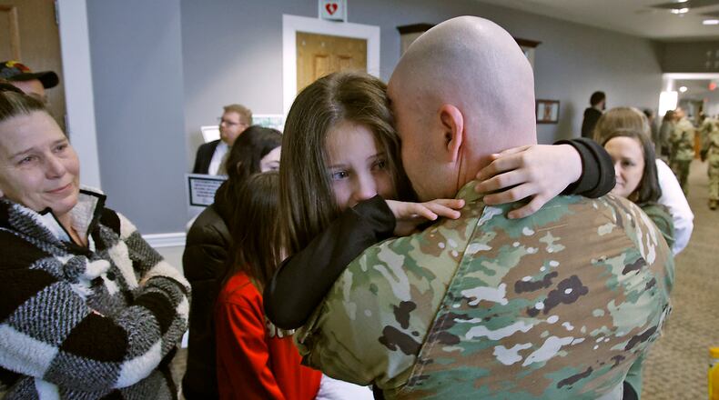 With tears in her eyes, Zoey Wildermuth hugs her father, Sgt. Darrick Cunningham, during a Call to Duty Ceremony Friday, Jan. 12, at the First Christian Church. Cunningham is being deployed with 30 other members of the Ohio National Guard's 1137th Signal Comapany, located in Springfield. BILL LACKEY/STAFF