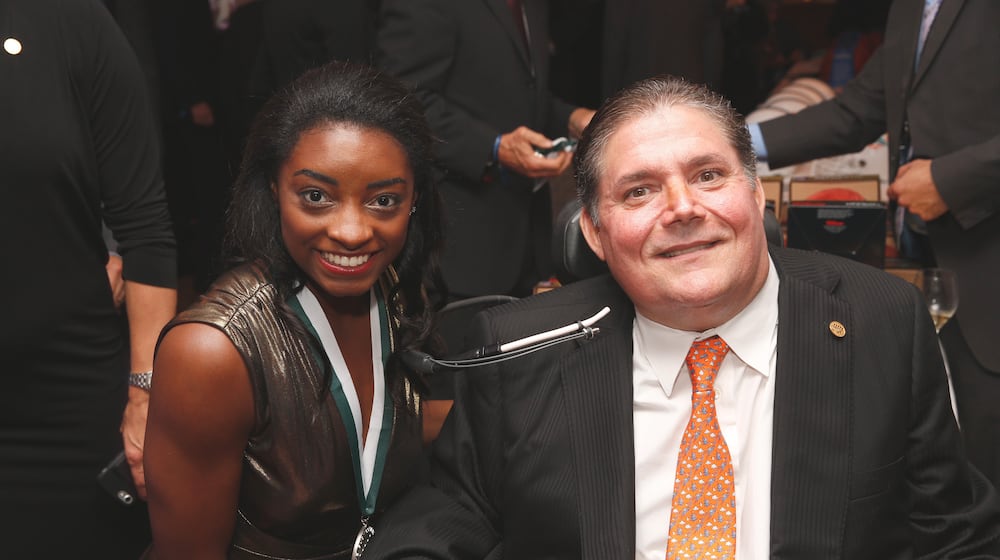 In this photo released by The Buoniconti Fund to Cure Paralysis, Olympic gold medal winning gymnast Simone Biles, left, poses with The Buoniconti Fund to Cure Paralysis President Marc Buoniconti at the 2018 Great Sports Legends Dinner, Sept. 24, 2018, to benefit the fund in New York. (The Buoniconti Fund to Cure Paralysis via AP)