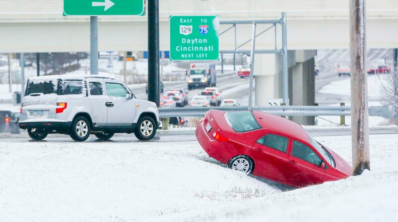 A car waits to be pulled out of a ditch along Cincinnati-Dayton Road in Liberty Twp. after a spring snow storm Wednesday, March 21.