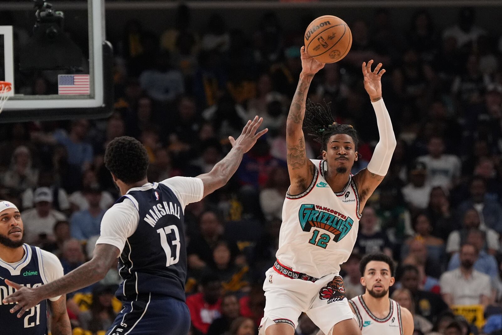 Memphis Grizzlies guard Ja Morant (12) passes the ball over Dallas Mavericks forward Naji Marshall (13) during the first half of an NBA play-in tournament basketball game Friday, April 18, 2025, in Memphis, Tenn. (AP Photo/George Walker IV)