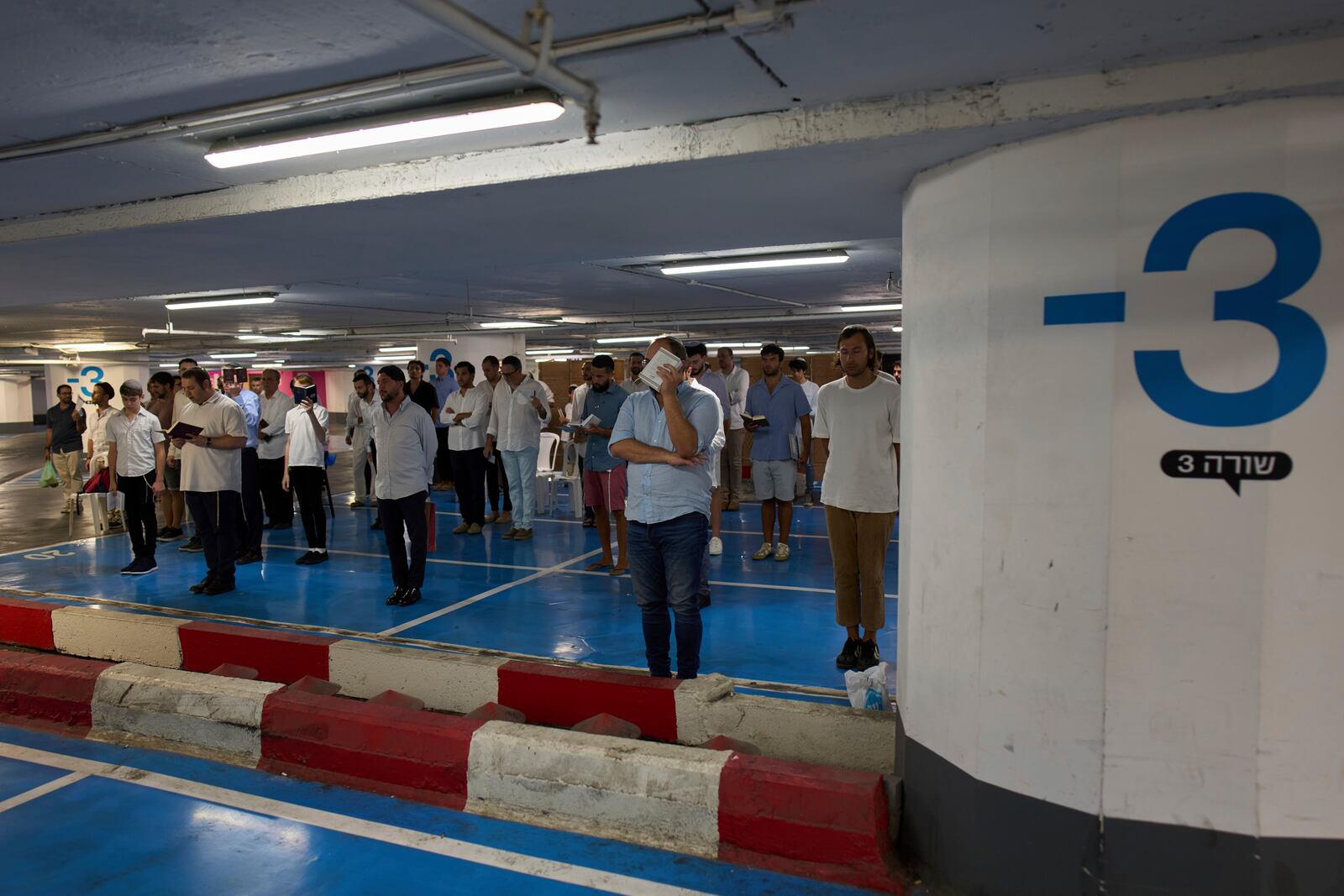 Jewish men attend a Shabbat prayer inside an underground parking for protection from missile strikes from Iran, in Tel Aviv, Israel, Friday, June 20, 2025. (AP Photo/Bernat Armangue)