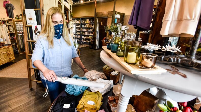 Debra Campbell at Fleurish Home on Main Street in Hamilton is using a UV light to sanitize products customers have touched and steaming garments tried on by customers as a measure to help combat germs in the store. NICK GRAHAM / STAFF