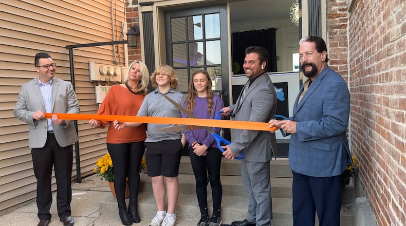Cryo Den, a cryotherapy spa, opens at 215 Main St. in Hamilton, Ohio. Pictured is the ribbon cutting with the Greater Hamilton Chamber of Commerce. Owner Jared Fox poses with the giant scissors outside the business's front door. MICHAEL D. PITMAN/STAFF