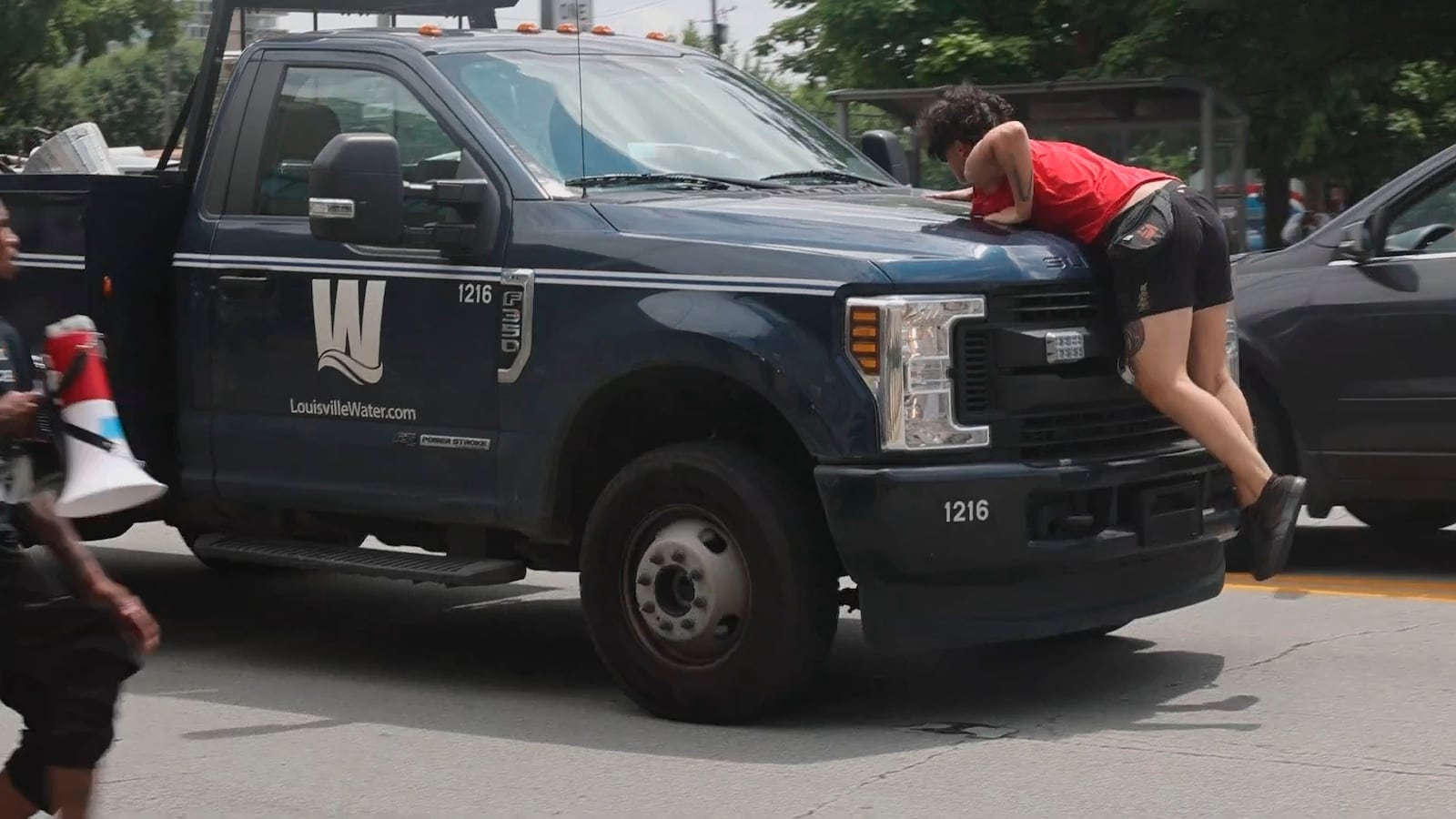 In this photo provided by WHAS-11 News, a protestor jumps on the hood of a Louisville Water truck outside the federal courthouse where ex-Kentucky police officer Brett Hankison, convicted of using excessive force during the deadly Breonna Taylor raid, is taking place, Monday, July 21, 2025, in Louisville, Ky. (Alyssa Newton/WHAS-11 News via AP)