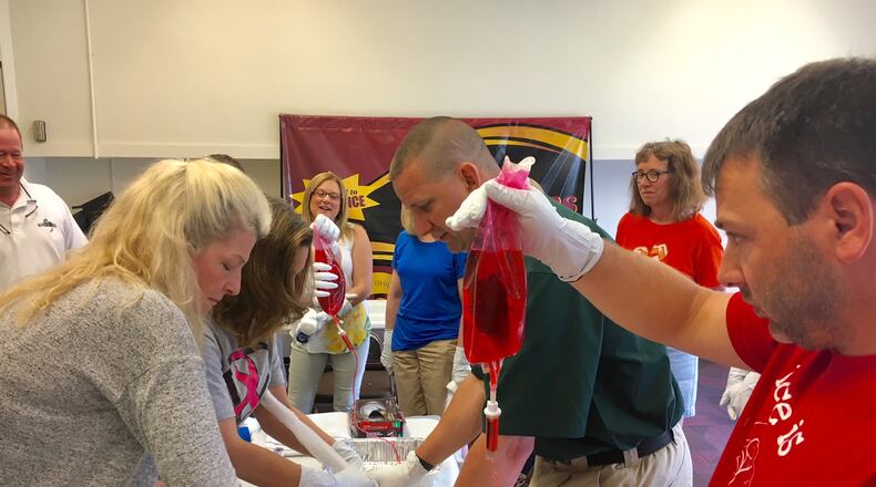 Atrium Medical Center in Middletown is teaching Butler County high school students and teachers how to treat bullet wounds and other possibly fatal injuries as part of some local schools’ overall emphasis on improving security and preparation for armed attacks on campus. Pictured are Ross school teachers who last year learned how to treat bullet wounds by using raw meat filled with a blood-like fluid.(Photo by Michael D. Clark/Journal-News)