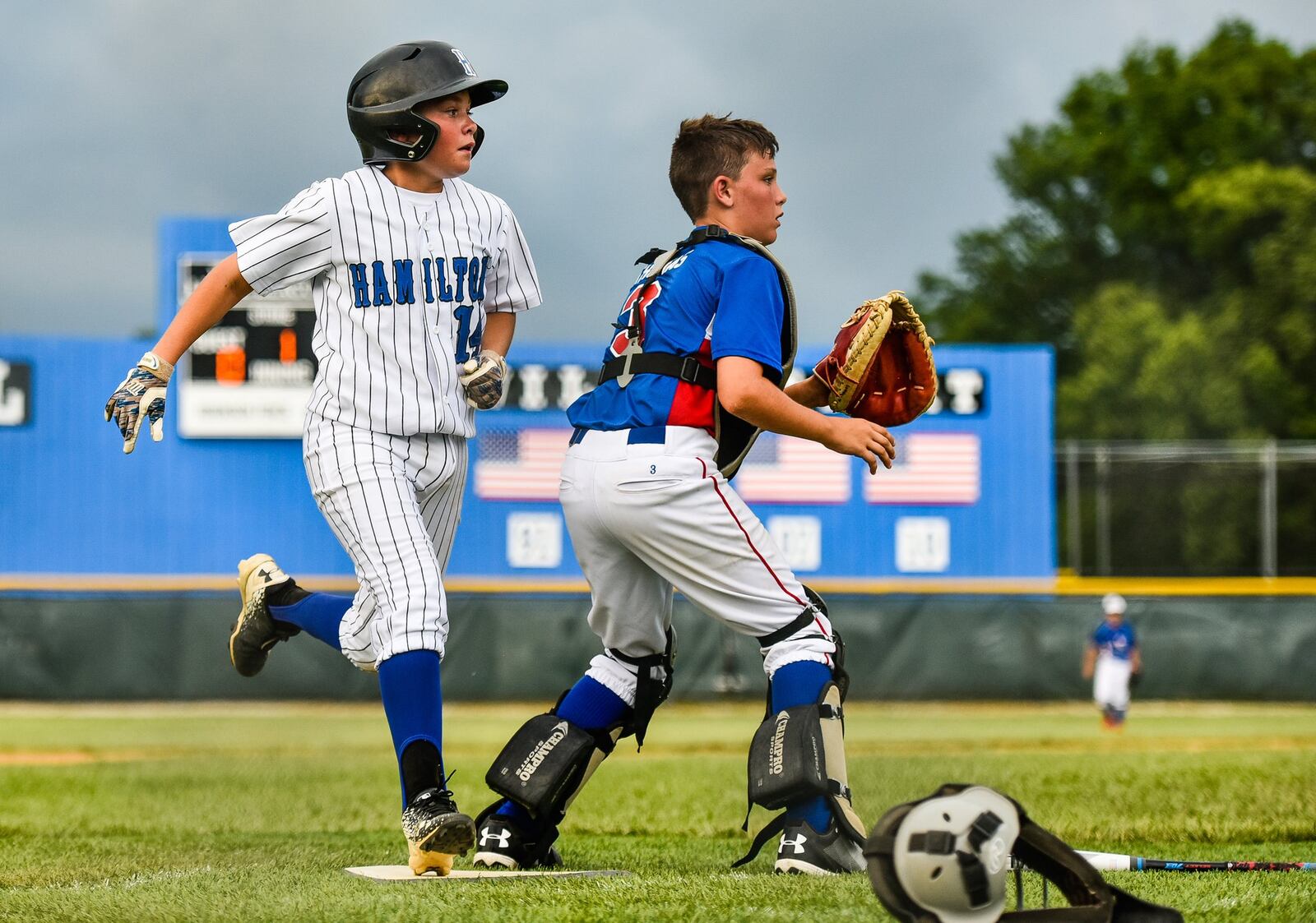 Hamilton West Side’s Nick Brosius scores a run ahead of a throw to Hamiton-Fairfield catcher Nolan Thomas during Tuesday night’s winners’ bracket final in the District 9 tournament at the West Side complex. NICK GRAHAM/STAFF
