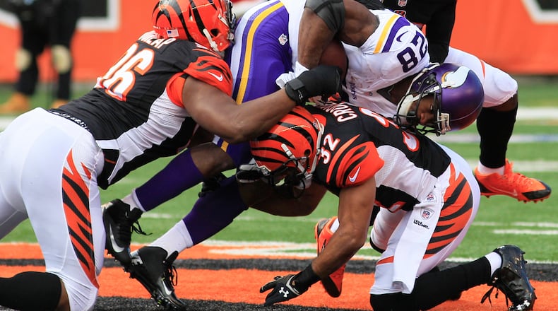 Minnesota Vikings running back Adrian Peterson (28) is tackled by Cincinnati Bengals defensive end Carlos Dunlap and defensive back Chris Crocker (32) during the first half of an NFL football game, Sunday, Dec. 22, 2013, in Cincinnati. Cincinnati won 42-14. (AP Photo/Tom Uhlman)