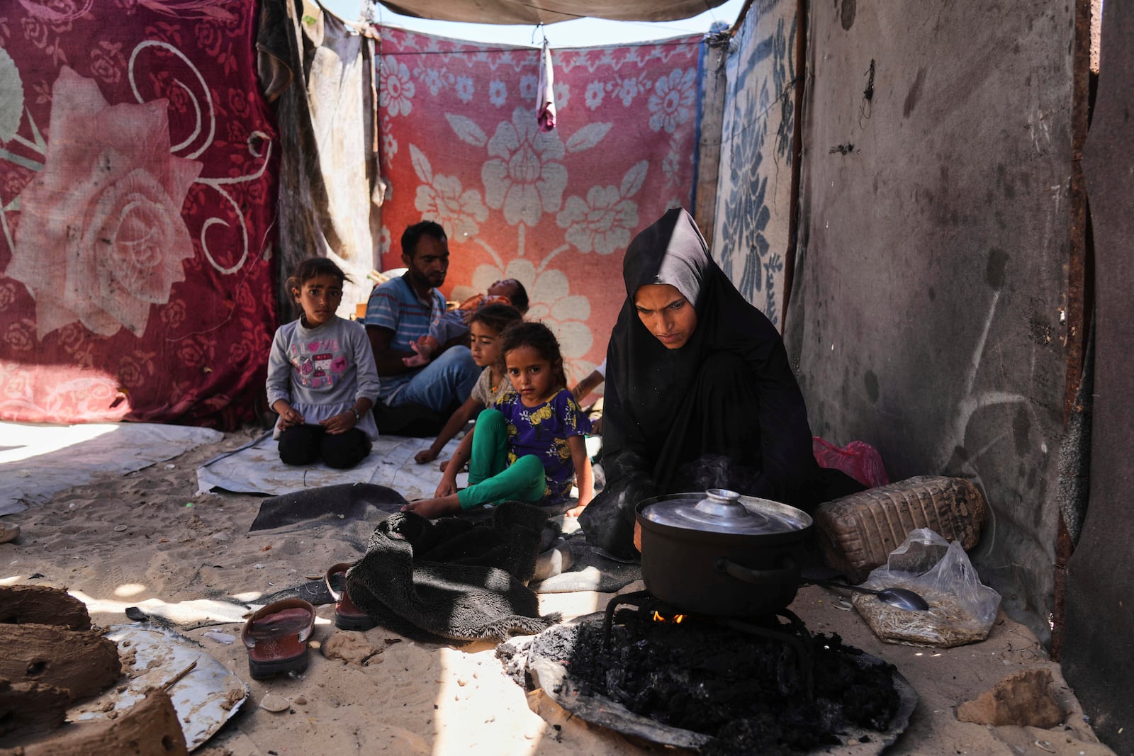 Nouf Al-Arja, 30, who suffers from malnutrition cook for her family inside their tent at a camp for displaces Palestinians in the Muwasi, Khan Younis, Gaza, Wednesday, May 21, 2025. (AP Photo/Abdel Kareem Hana)