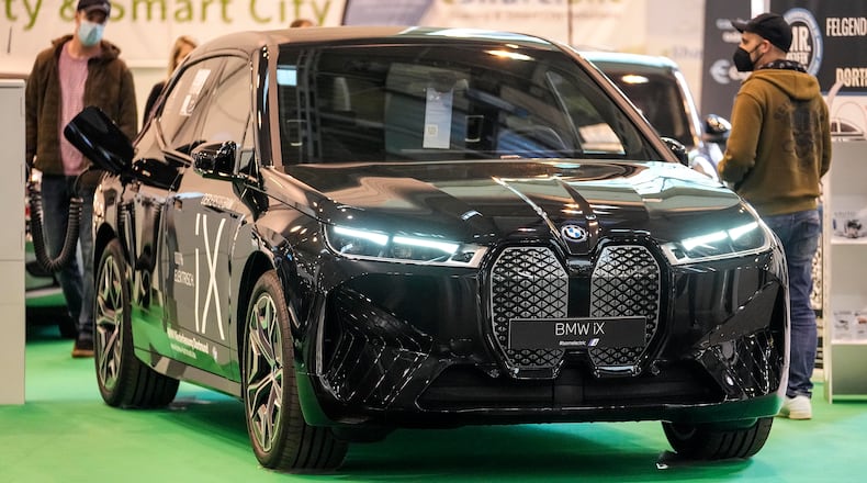 Visitors watch the new full electric car BMW iX iat the Motor Show in Essen, Germany, Thursday, Dec. 2, 2021. (AP Photo/Martin Meissner)