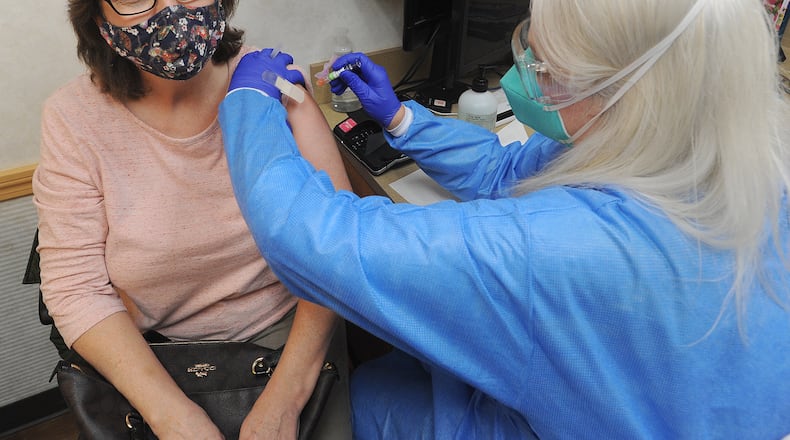 Denisea Mount, a nurse practitioner at the MinuteClinic inside a CVS in Centerville, Ohio, gives a flu shot to patient Tracy Young earlier this fall. MARSHALL GORBY\STAFF