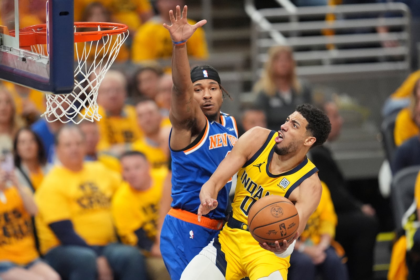 Indiana Pacers guard Tyrese Haliburton (0) shoots the ball past New York Knicks guard Miles McBride, left, during the second half of Game 4 of the Eastern Conference finals of the NBA basketball playoffs in Indianapolis, Tuesday, May 27, 2025. (AP Photo/Michael Conroy)