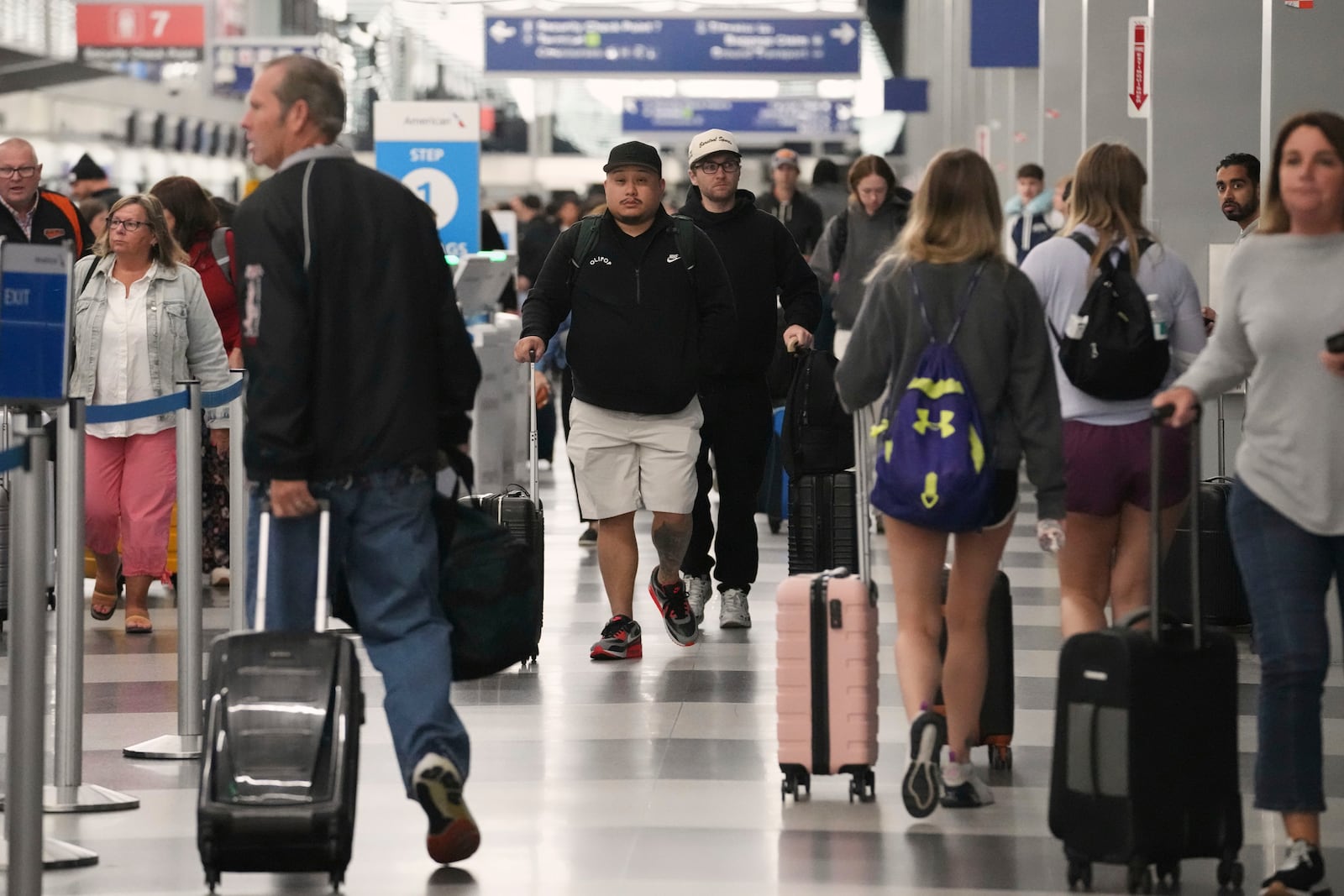 Travelers carry their luggage through at O'Hare International Airport in Chicago, Friday, May 23, 2025. (AP Photo/Nam Y. Huh)
