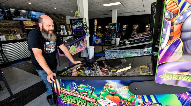 Pinball Garage owner Brad Baker plays the brand new Teenage Mutant Ninja Turtles pinball game Thursday, June 25, 2020. Pinball Garage is now open in downtown Hamilton and offers a large selection of pinball machines to play along with a bar with rotating beer selection. NICK GRAHAM / STAFF