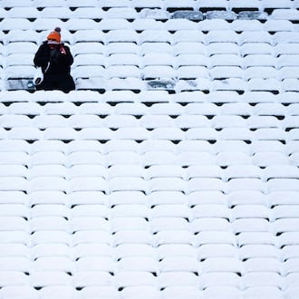 A fan sits in the stadium seats covered in snow before an NFL football game between the Cincinnati Bengals and the Baltimore Ravens, Sunday, Dec. 14, 2025, in Cincinnati. (AP Photo/Carolyn Kaster)