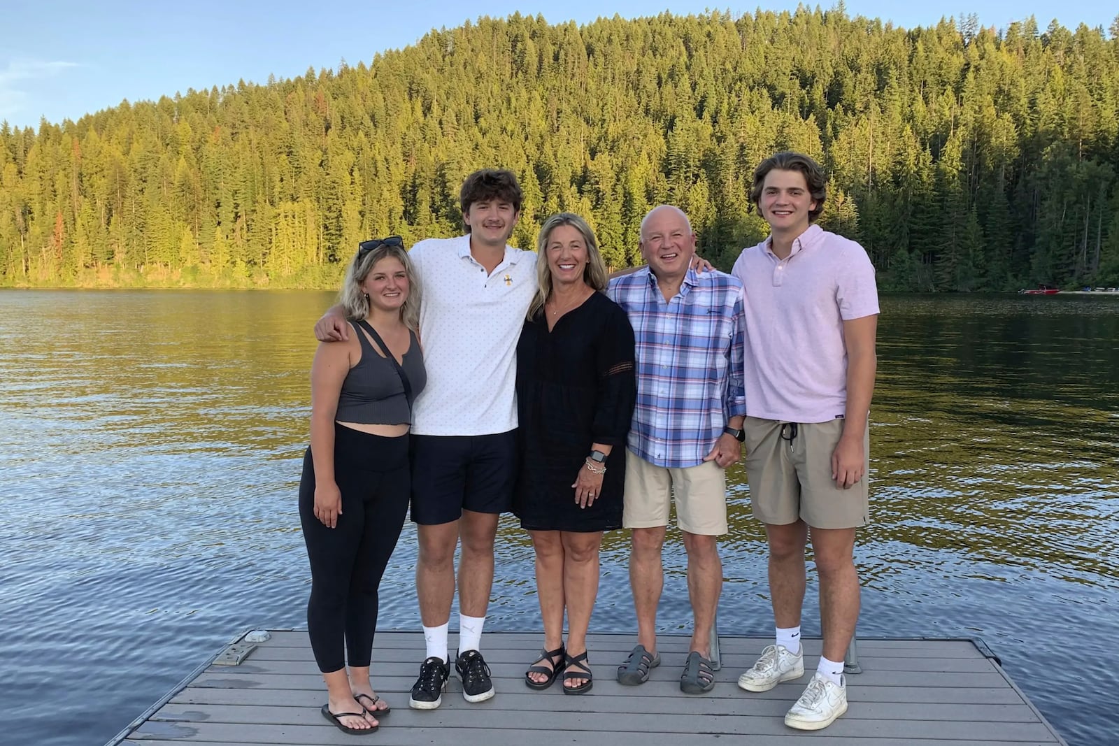 In this photo provided by Stacy Chapin, triplets Maizie, left, Ethan, second from left, and Hunter, right, pose with their parents Stacy and Jim Chapin at Priest Lake in northern Idaho in July 2022. (Stacy Chapin via AP)