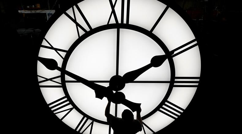 Electric Time technician Dan LaMoore puts a clock hand onto a 1000-lb., 12-foot diameter clock constructed for a resort in Vietnam, Tuesday, March 9, 2021, in Medfield, Mass. Daylight saving time begins at 2 a.m. local time Sunday, March 14, 2021, when clocks are set ahead one hour. (AP Photo/Elise Amendola)