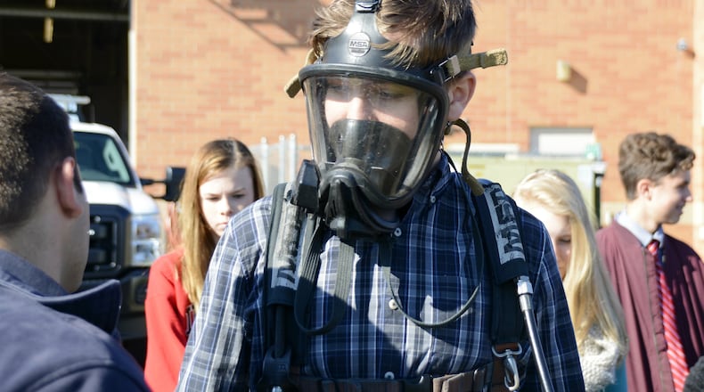 Trent Gleason, a Fairfield freshman, tries on a SCBA mask and tank on Thursday during a career day at the Fairfield Twp. administration building where they learned about township government, including the police and fire departments. Around 200 Fairfield freshmen learned were involved in a career day with Junior Achivement of OKI in various fields out in the community. About 20 visited the Fairfield Twp. Administration offices. MICHAEL D. PITMAN/STAFF