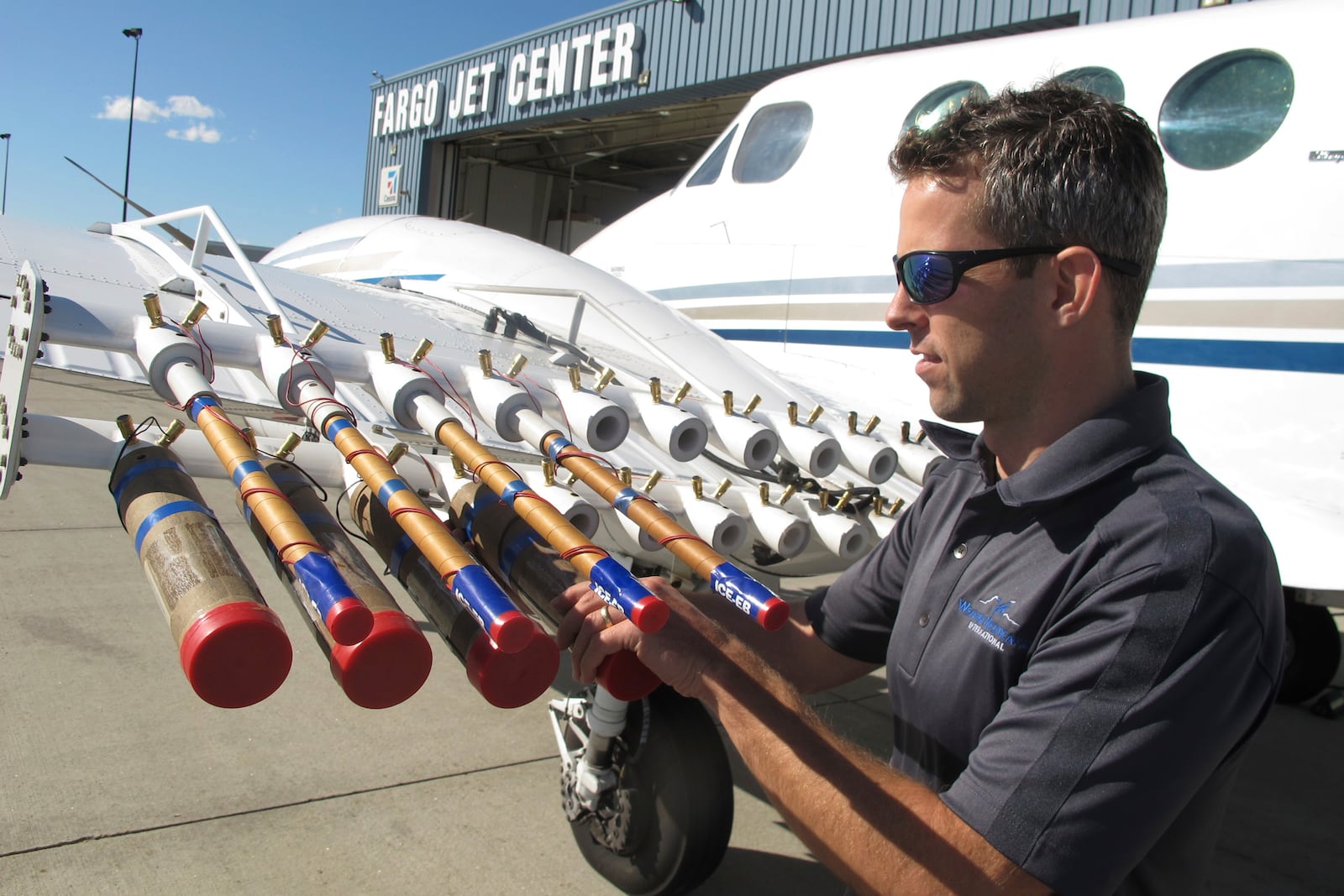 FILE - Jody Fischer, director of flight operations for a North Dakota-based cloud seeding business, adjusts flares used for a seeding on a plane outside the company headquarters in Fargo, N.D., Sept. 20, 2017. (AP Photo/Dave Kolpack, File)