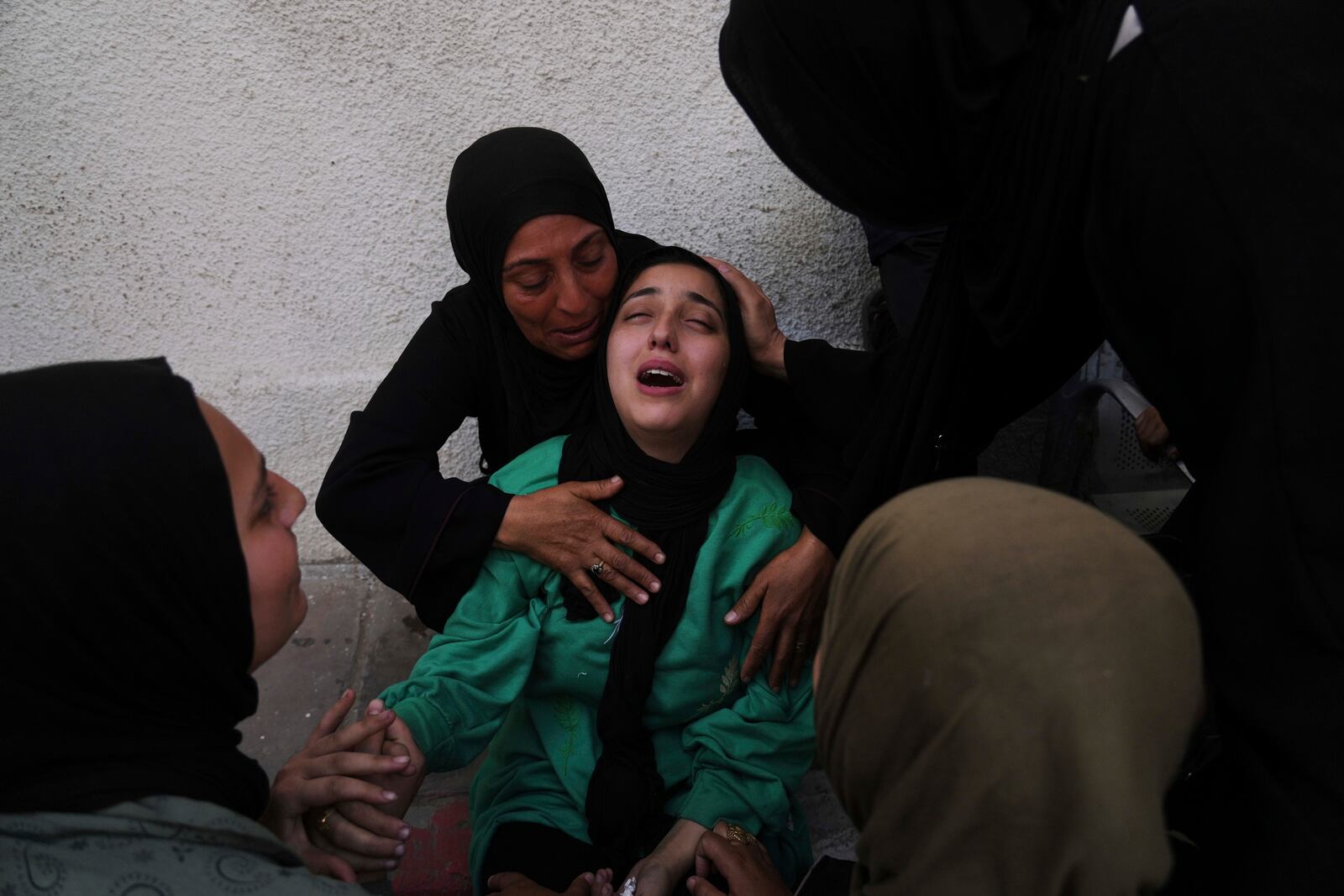 Walaa Al-Kilani, center, mourns her mother and brother, who were killed when an Israeli military strike hit a school sheltering displaced residents, at Al-Shifa Hospital in Gaza City, Monday, May 26, 2025. (AP Photo/Jehad Alshrafi)