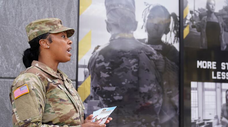The U.S. Army National Guard member Sgt. Jessica Jones, an officer with the Metropolitan Police Department, distributes brochures to people walking by during training, Thursday, April 21, 2022 in Washington. (AP Photo/Mariam Zuhaib)