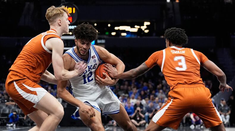 Duke forward Cameron Boozer drives to the basket between Texas center Matas Vokietaitis, left, and forward Dailyn Swain during the second half of an NCAA college basketball game, Tuesday, Nov. 4, 2025, in Charlotte, N.C. (AP Photo/Chris Carlson)