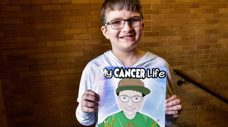 Matthew Harrison, a sixth-grader at Chamberlain Middle School in Carlisle, holds a book he in which he is the star. Sarah Curry Rathel and illustrator Bob Kelly, with Smile Books Project, created the book, “My Cancer Life,” to tell the story of Harrison and his life dealing with Leukemia. NICK GRAHAM/STAFF