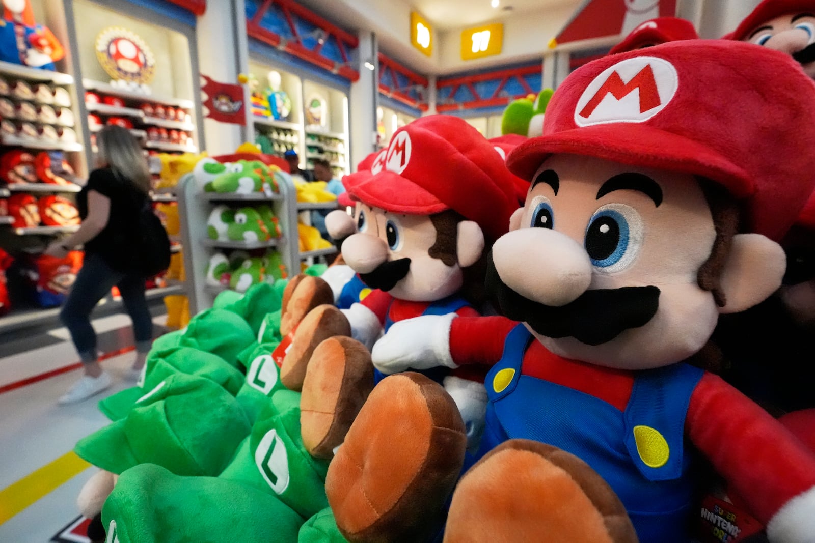 A shopper looks over merchandise for sale in a gift shop at Super Nintendo World at Epic Universe Theme Park at Universal Resort Orlando Thursday, April 10, 2025, in Orlando, Fla. (AP Photo/John Raoux)