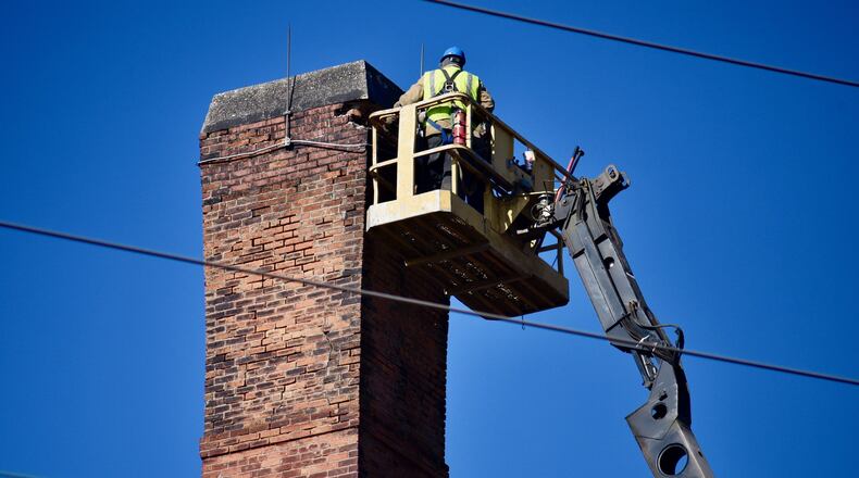 A crew from Vickers Demolition worked off an aerial platform about 90 feet in the air Sunday as they used a jackhammer to chisel and chip away a few bricks at a time on both smoke stacks as they prepare to bring them down on Monday. A Vickers employee said this was a result of the close proximity to power lines and said the tallest tower is about 90 feet tall. NICK GRAHAM/STAFF