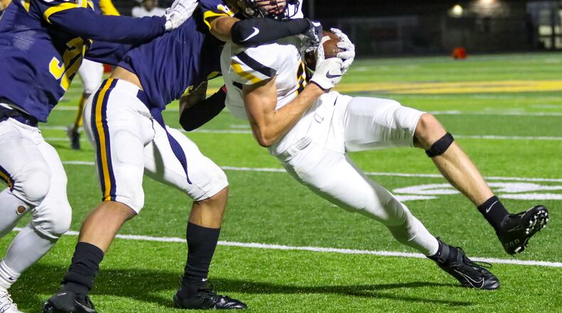 Centerville High School wide receiver Will Linkhart is tackled by Springfield's Dayveon Bates (3) and Delian Bradley (36) on Thursday night at Springfield High School. The Wildcats won 41-28. CONTRIBUTED PHOTO BY MICHAEL COOPER