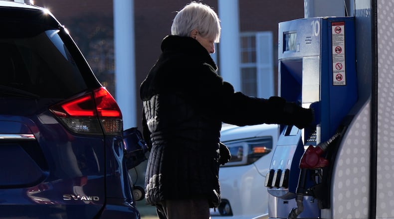 A woman checks gas prices before she fills up her vehicle's gas tank at a gas station in Buffalo Grove, Ill., Wednesday, Jan. 7, 2026. (AP Photo/Nam Y. Huh)