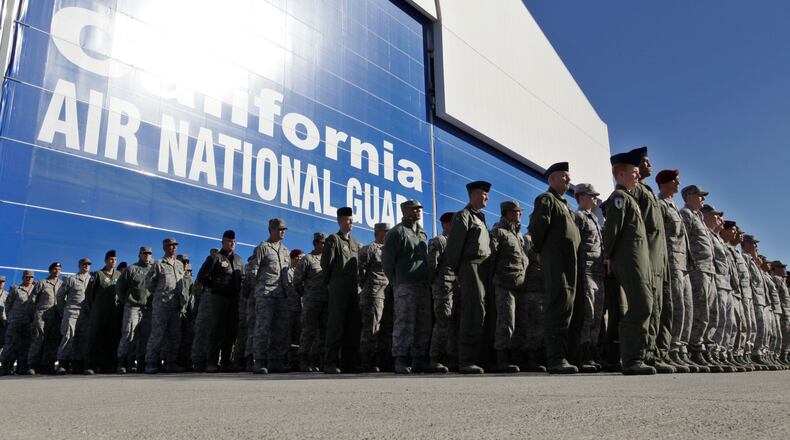 FILE - In this Nov. 30, 2011 file photo, California Army National Guard soldiers watch the arrival of the body of soldier Sean Walsh, who died on Nov. 16 during a combat operation in Afghanistan, at Moffett Federal Airfield in Mountain View, Calif. Nearly 10,000 California National Guard soldiers have been ordered to repay huge enlistment bonuses a decade after signing up to serve in Iraq and Afghanistan, the Los Angeles Times reported Saturday, Oct. 22, 2016. (AP Photo/Paul Sakuma, File)