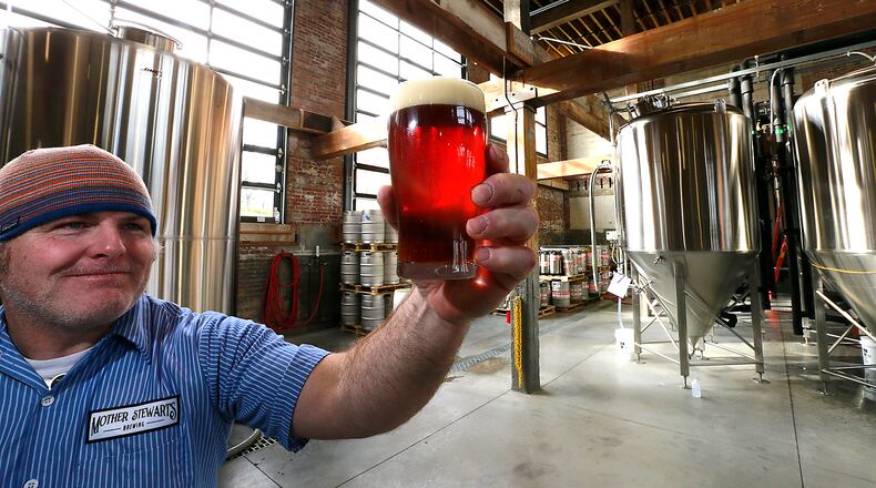 John Loftis holds up a glass of Mother Stewart’s beer to the light in their brew house in Springfield. BILL LACKEY/STAFF