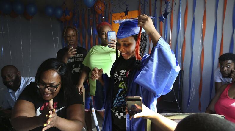 Sharawn Vinson, front left, and family members and friends cheer for her daughter, Maddison Washington, 11, as they watch her virtual graduation from middle school in the living room of their three-bedroom apartment in the Brooklyn borough of New York on Friday, Aug. 21, 2020. After months of pandemic isolation and living with the fear of hunger as bills piled up, Vinson and her kids continued volunteering to help feed their own community. (AP Photo/Jessie Wardarski)