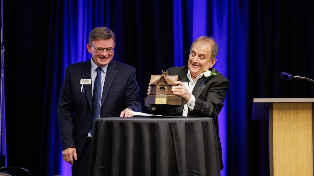Frank Pfirman, the founder of the Hamilton company Matandy Steel, lifts the Hamilton Community Foundation's David L. Belew Legacy Award on Wednesday, Oct. 22, 2025. Hamilton Community Foundation President and CEO John Guidugli looks on. The ceremony was held at the Courtyard by Marriott in downtown Hamilton. (PHOTO PROVIDED by Hamilton Community Foundation via Tom Pate)