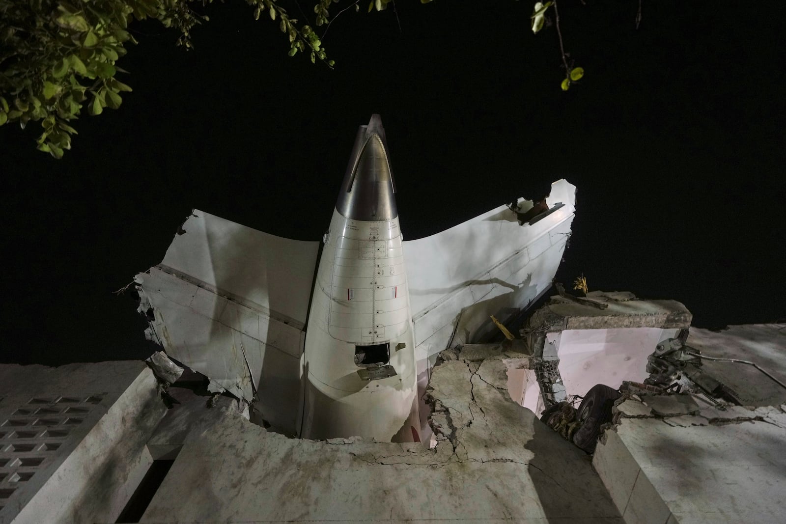 FILE -The tail of the airplane is seen stuck in a building at the site of an airplane that crashed in India's northwestern city of Ahmedabad in Gujarat state, June 12, 2025. (AP Photo/Ajit Solanki, File)